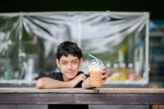 Photo adolescent garçon buvant du jus de fruit dans le parc camping l'heure d'été