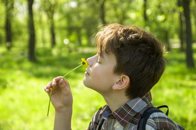 Adolescent garçon profitant de la nature au printemps parc heureux jeune homme sur fond flou vert