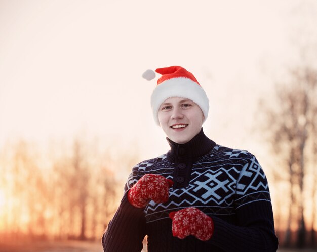 Adolescent heureux dans le chapeau du père Noël en plein air