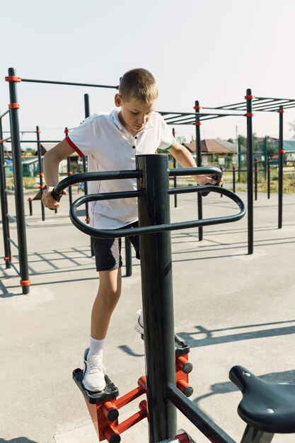 Adolescent heureux de garçon dans le t-shirt blanc travaillant sur les sports.