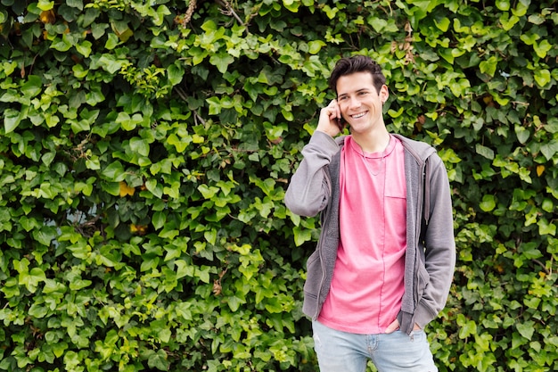 Un adolescent heureux sourit en parlant par téléphone