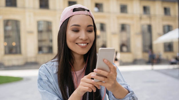 Adolescent heureux utilisant un téléphone portable dans la rue