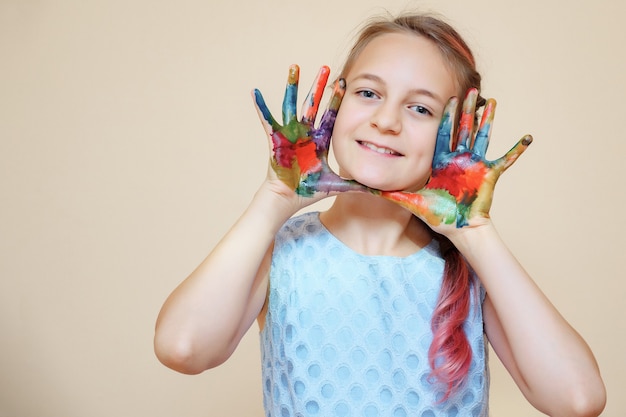 Adolescent heureux avec le visage et les mains dans des peintures colorées souriant à la caméra