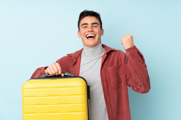 Adolescent homme caucasien isolé sur violet en vacances avec valise de voyage