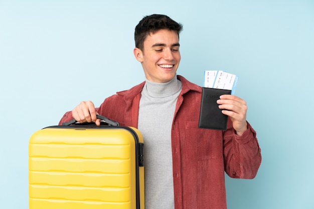 Adolescent homme caucasien sur mur violet en vacances avec valise et passeport