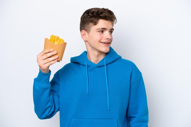 Adolescent homme russe tenant des pommes de terre frites isolé sur fond blanc à côté