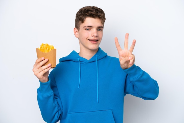 Adolescent homme russe tenant des pommes de terre frites isolé sur fond blanc heureux et comptant trois avec les doigts