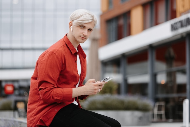 Adolescent intelligent et confiant avec son téléphone à l'extérieur. Portrait de jeune hipster blonde avec son téléphone.