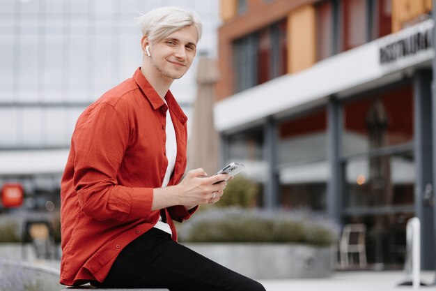 Adolescent intelligent et confiant avec son téléphone à l'extérieur. Portrait de jeune hipster blonde avec son téléphone.