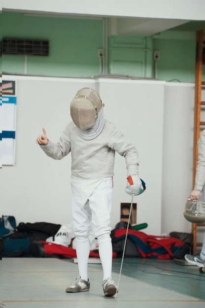 Adolescent jeune escrimeur en costume blanc et masque de protection