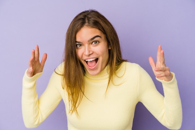 Adolescent jeune fille maigre caucasienne sur espace violet recevant une agréable surprise, excité et levant les mains.