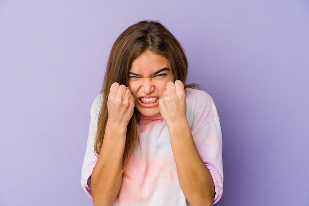 Adolescent jeune fille maigre caucasienne sur violet montrant le poing, expression faciale agressive.