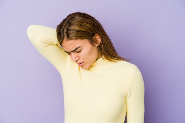 Adolescent jeune fille maigre de race blanche sur fond violet ayant une douleur au cou due au stress, en massant et en le touchant avec la main.