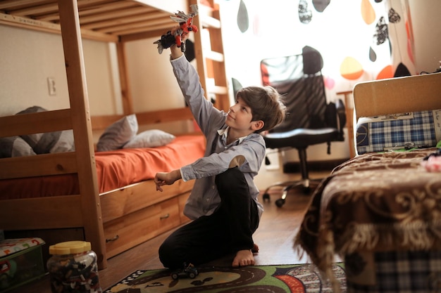 Un adolescent joue avec un créateur sur le sol dans une vraie chambre d'enfant.