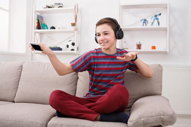 Adolescent joyeux appréciant la musique dans des écouteurs à la maison. Temps de repos