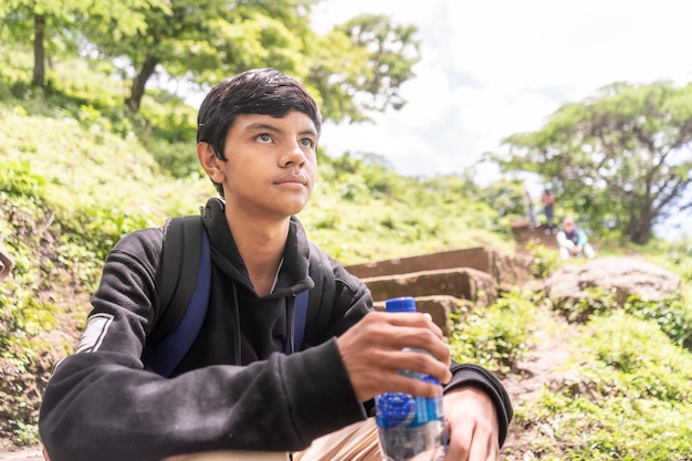 Adolescent latino assis sur les gradins dans une région montagneuse