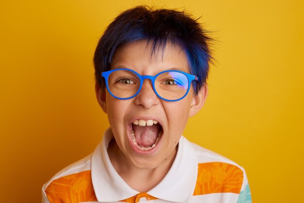 Adolescent avec des lunettes criant sur fond jaune clair isolé