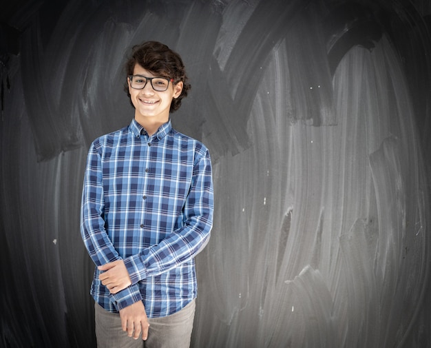 Adolescent avec des lunettes devant le tableau de la classe