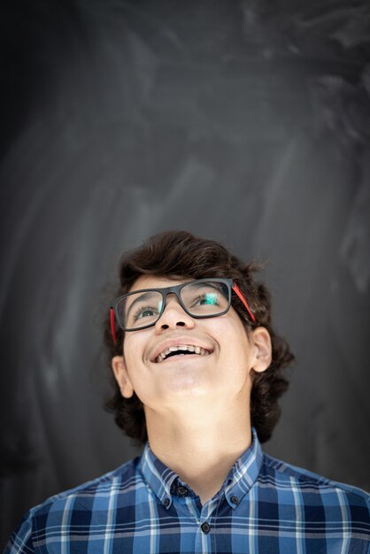 Adolescent avec des lunettes devant le tableau de la classe