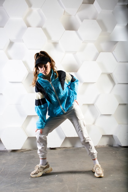 Adolescent mignon danse hip-hop dans un pantalon réfléchissant, dans un studio avec éclairage au néon. Affiche de couleur de danse.