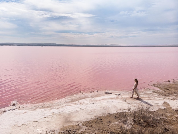 Adolescent mignon femme vêtue d'une robe blanche marchant sur un magnifique lac rose