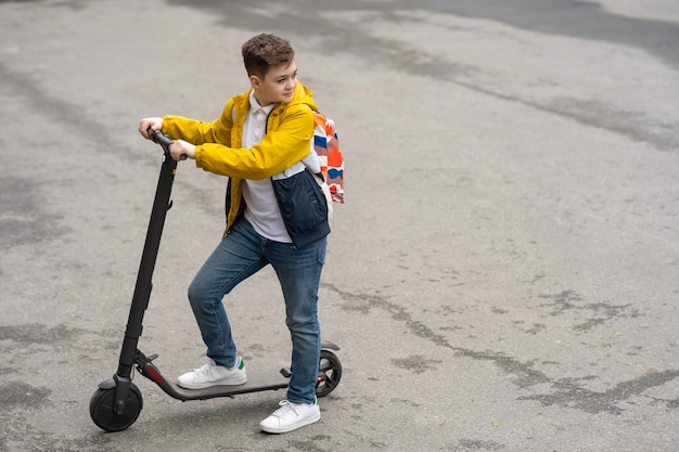 Adolescent moderne sur scooter électrique.