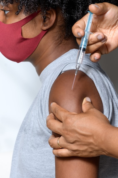 adolescent noir portant un masque de protection contre covid19 montre la marque du vaccin