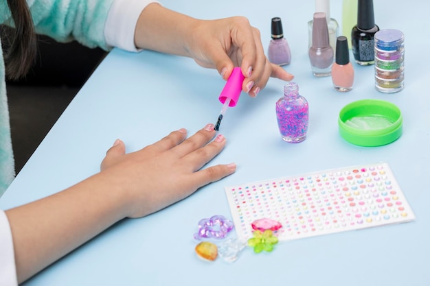 Adolescent peignant ses ongles à la maison avec des produits de vernis