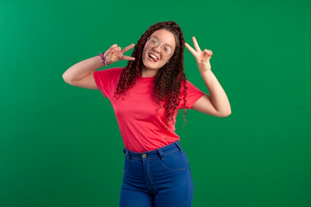 Adolescent portant des lunettes dans des poses amusantes dans un studio photo avec un fond vert idéal pour le recadrage