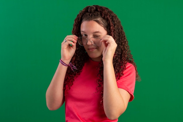 Photo adolescent portant des lunettes dans des poses amusantes dans un studio photo avec un fond vert idéal pour le recadrage
