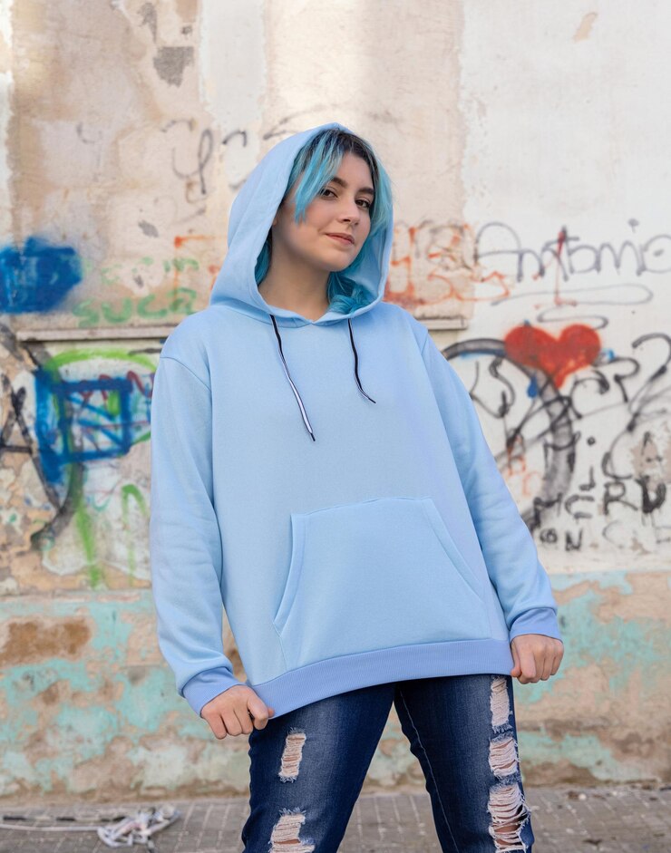 Photo adolescent portant un sweat à capuche surdimensionné bleu clair et un jean regardant dans la caméra une adolescente aux cheveux bleus reste à l'extérieur contre un mur de graffitis maquette de vêtements concept de hipster et d'adolescence