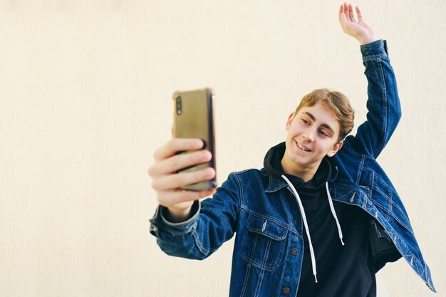 Un adolescent prend un selfie - un jeune homme se prend en photo sur un smartphone