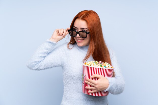 Adolescent rousse femme avec des lunettes 3d et tenant un gros seau de pop-corn