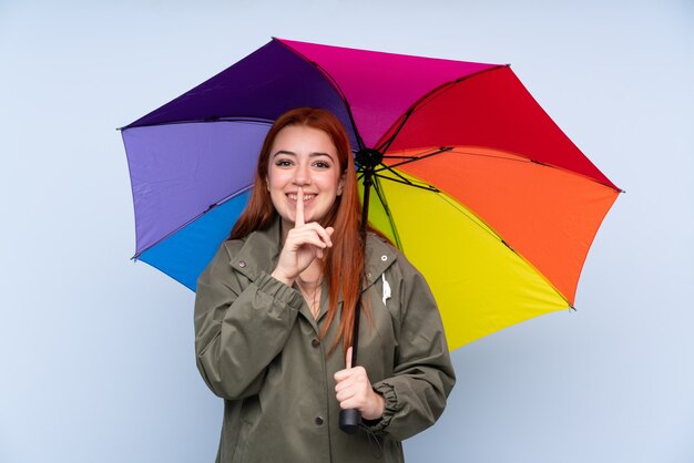 Adolescent rousse femme tenant un parapluie faisant le geste de silence