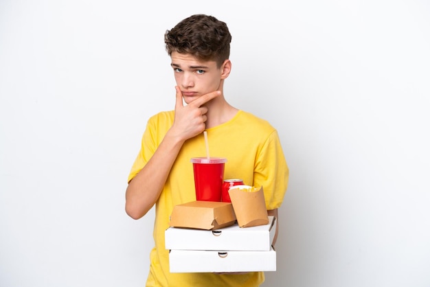 Adolescent russe man holding fast food isolé sur fond blanc pensant