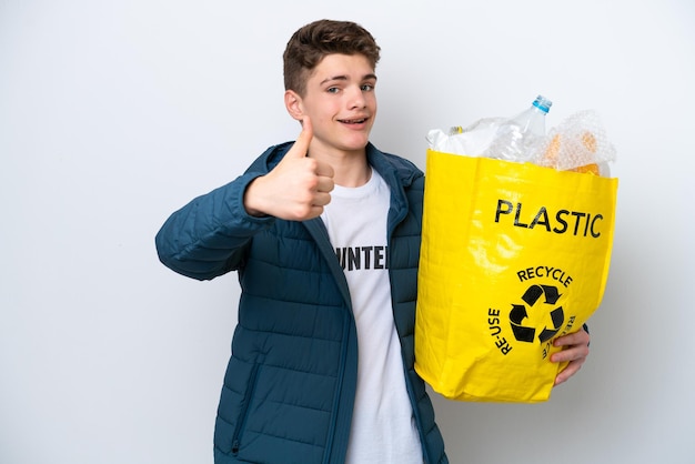 Adolescent russe tenant un sac plein de bouteilles en plastique à recycler sur fond blanc avec le pouce levé parce que quelque chose de bien s'est produit