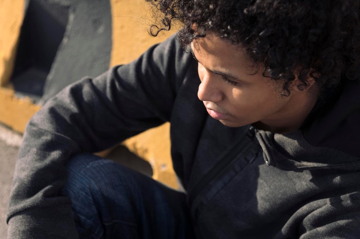 Photo un adolescent sérieux assis dans une rue urbaine.