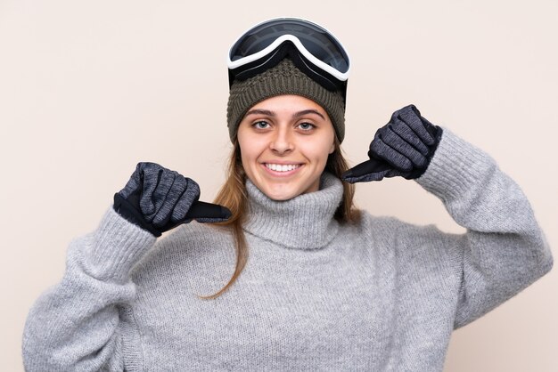 Adolescent skieur femme avec des lunettes de snowboard sur mur isolé fier et satisfait de lui-même