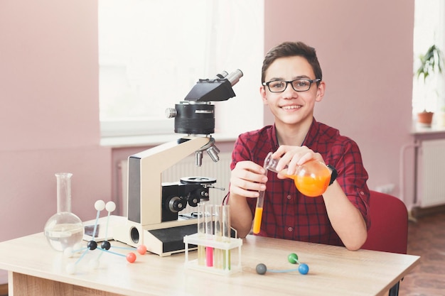 Adolescent souriant faisant des recherches chimiques avec des réactifs en laboratoire, espace de copie. Développement précoce, bricolage, concept d'éducation. L'éducation des tiges.