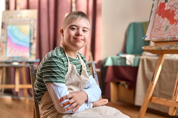 Un adolescent souriant avec le syndrome de Down souriant à la caméra dans un studio d'art