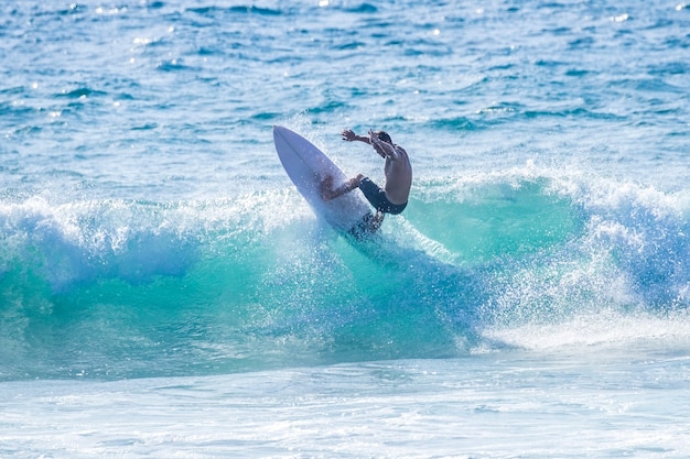 Adolescent surfant à la vague à tenerife playa de las americas - combinaisons rouges et belle et parfaite vague - freestyle et faire des tours