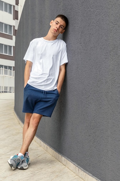 Photo adolescent en t-shirt blanc, short bleu et baskets à l'extérieur