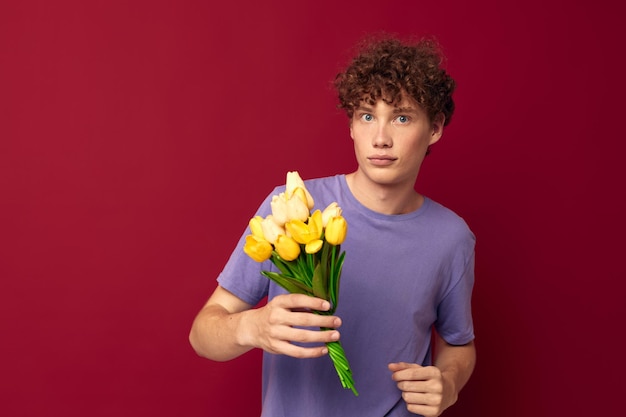 Adolescent tenant un bouquet de fleurs jaune violet tshirts fond rouge inchangé