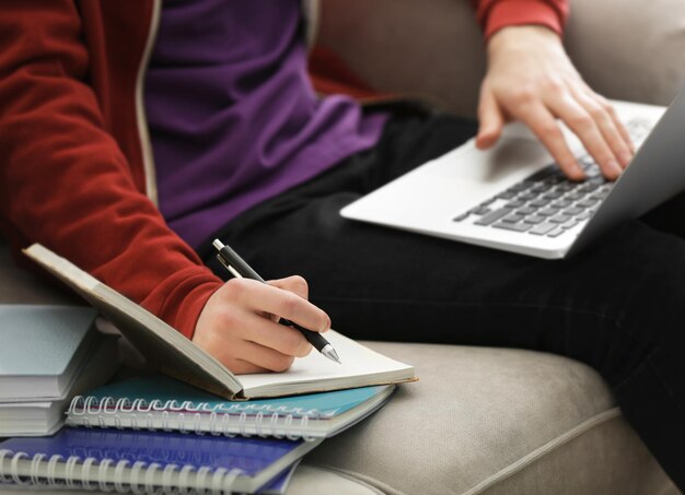 Adolescent travaillant avec un ordinateur portable tout en faisant des cours à la maison en gros plan