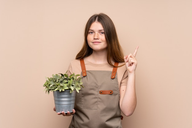 Adolescent ukrainien jardinier fille tenant une plante pointant avec l'index une excellente idée