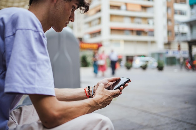 Un adolescent utilisant son smartphone pour consulter les réseaux sociaux et être en contact avec ses amis