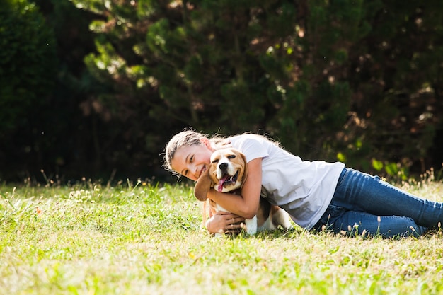Une adolescente adorable joue avec un chien beagle dans le parc