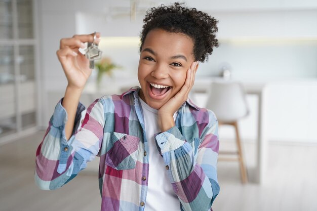 Une adolescente afro-américaine excitée montrant les clés de la première maison neuve Service de location immobilière