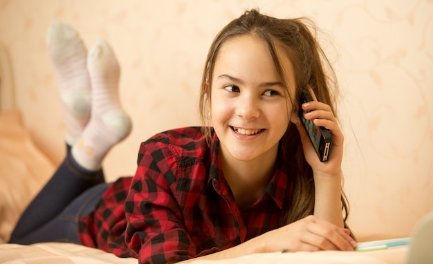 Photo adolescente allongée dans la chambre et parlant par téléphone