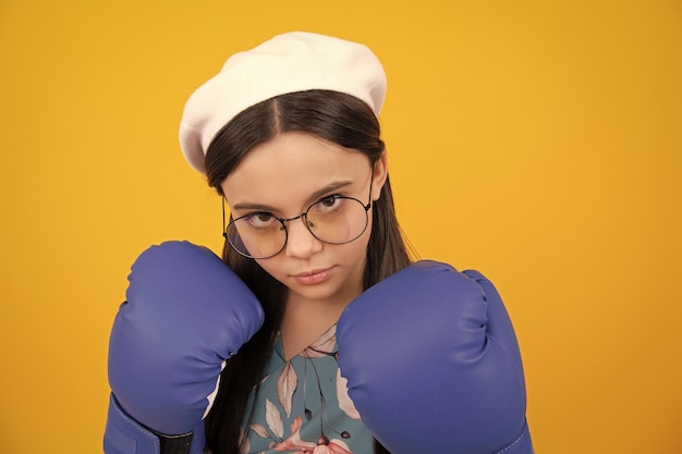 Adolescente amusante boxeuse dans des gants de boxe sur fond jaune isolé Funny girl boxer dans des gants amusants studio de boxe tourné isolé sur fond jaune